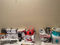 Photo showing various small kitchen appliances and utensils including KitchenAid slicer/shredder, candy melting pot, warming pot, and utensils.