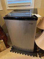 Front view of the compact stainless steel Arctic King refrigerator with black top.
