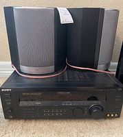 Front view of Sony AV receiver with two JBL speakers behind it.