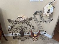 Set of three metal wall decor pieces shown against a beige wall, including a large ornate piece, metal musical note, and Harley plaque.
