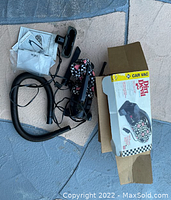 Dirt Devil handheld car vacuum cleaner, power cord, flexible hose, two attachments, manual, and original box on a blue and beige surface.