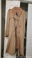 Front view of vintage beige trench coat showing double-breasted buttons, belt, and collar detail.