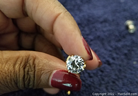 Close-up of the round natural diamond showing the cut and facets in a metal mounting.