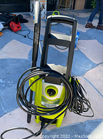 GreenWorks electric chainsaw grinder showing handle, cord, and body in bright green and black colors