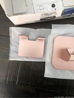 Pink/rose gold charging stand piece and base with packaging box in background.