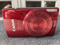 Front of the red Canon PowerShot Digital ELPH 190 IS camera showing lens, flash, and branding