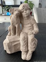 Front view of carved sculpture showing boy and dog seated on block base