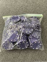 Two resealable bags filled with purple clay poker chips with white patterns, each bag marked with text indicating the quantity and/or type.