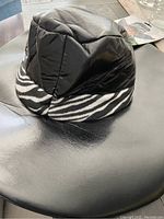 Black synthetic hat with zebra print brim on black surface