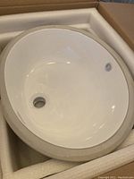 White porcelain round undermount sink inside protective foam packaging.