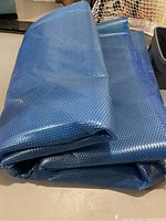 Folded blue solar pool cover with visible bubble wrap texture.