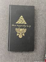Front cover of black hardcover book with gold foil design and handwritten band name
