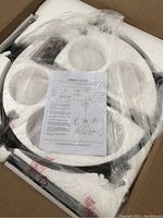 Wagon wheel style light fixture and parts in original packaging with instructions on top wrapped in plastic.