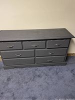 Front view of painted wood dresser with 7 drawers, gray color, metal handles, one handle missing