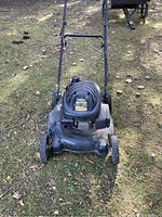 Front view of Yardworks gas lawnmower showing black engine cover with vents and four wheels on grass.
