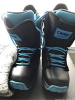 Front view of both new black youth snowboard boots with blue laces and Capix logo on tongues.