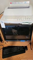 Full view of the Dell monitor with keyboard and mouse on desk, and Brothers electronic typewriter placed on top of the monitor.