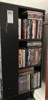 DVDs arranged on a black shelving unit, showing multiple rows filled with DVD cases, some stacked horizontally on top of vertical rows.