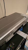 Front and side angle of the silver Emerson DVD CD combo player model EWD2003 showing control buttons and disc tray.