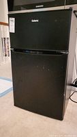 Full view of the black Galanz refrigerator freezer combo showing general condition.