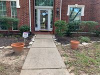 Front porch showing two large clay pots positioned on either side of the walkway's start.