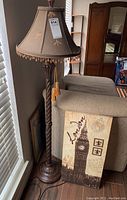 Photo showing lamp with beaded shade and tassel pulls beside London canvas art
