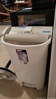Front view of Steel City paper shredder showing white wastebasket and beige control panel with basic buttons and branding.