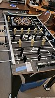 Full view of the foosball table with the dartboard placed on top, showing player figures, playing rods, and outer structure.