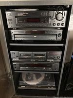 Shelf of black Sony rack-mount components and Technics turntable at bottom