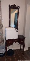 Full view of wooden accent table with items on top, showing design and condition.