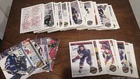 Wide photo showing multiple OPC hockey cards spread on a wooden surface in partial stacks
