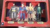 Photo of transport box containing 4 DC Comics bendable figures: Batman, Superman, Wonder Woman, Green Lantern, all visible through clear plastic window.