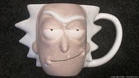 Front view of a ceramic coffee mug shaped like the cartoon character Rick Sanchez's face from Rick and Morty. Shows the detailed 3D facial features including eyes, nose, mouth, and spiked hair shape extending from the mug body.