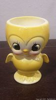 Front view of yellow chick egg cup showing detailed face and wings.