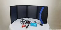 Folded solar panel kit partially open laid on flat surface showing 4 connected solar panels and attached wiring with charge controller and clips.