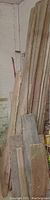 Tall, long wooden barn planks leaned against a wall, showing natural aging and wear consistent with reclaimed barn wood. Pieces are between 9 and 10 feet long.