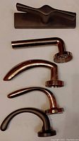 Photo showing four silver-colored curved lever door handles with round bases and one black T-shaped handle with rectangular base, all used.