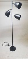 Full view of the black metal 3-light floor lamp showing all lamp heads and base.