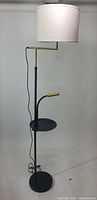 Floor lamp with white drum shade attached, showing integrated table and adjustable reading lamp with gold accent.