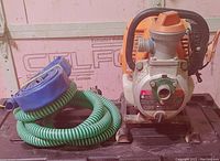 Front view of the Generac pump with green intake hose and blue discharge hose coiled beside it, showing overall condition and included accessories.