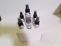 Front view of six new hand sanitizer bottles from Alpine brand: five small and one large with owl artwork