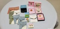 Full lot overview with all jewelry items laid out on white fabric background showing individual boxed items and carded necklaces and bracelets.