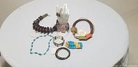 Full view of all jewellery and accessories in the lot arranged on a white round display stand, showing variety of styles and colors.