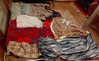 Seven ladies scarves laid out on a bed showing various colors and patterns including floral, plaid, and abstract.