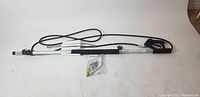 Full length pressure washer wand with attached hose and black handle, laid out on floor with accessories near center.