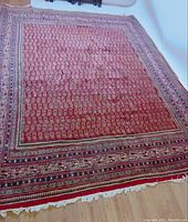 Overall view of red Persian hand made Sorough rug showing paisley pattern and border details.