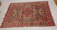 Full view of the silk Persian rug laid flat on the floor showing the central medallion and borders.