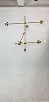 Front view of the Sputnik chandelier showing intersecting brass rods and clear glass globes.