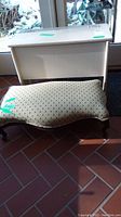Front angle of wood storage bench and upholstered ottoman showing the bench's rectangular shape and the ottoman's padded seat with dotted fabric.