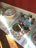 Lot items including brass dish, brass horn, metal containers, candle snuffer, brass medallions, glass containers, and assorted items